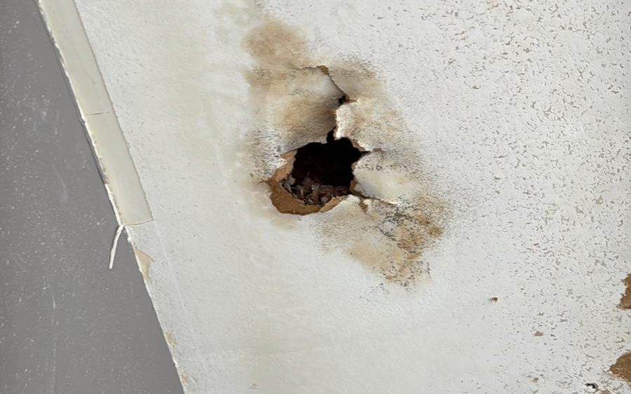 Water-damaged ceiling with a hole that needs drywall repair