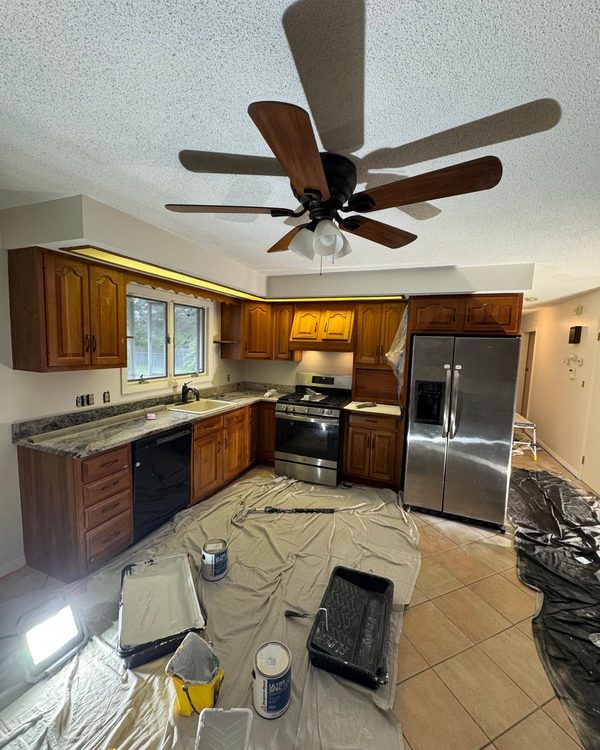 Kitchen with original wood cabinets, protected with drop cloths before painting