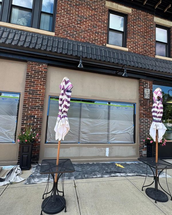 Storefront masked with plastic and tape during exterior repaint