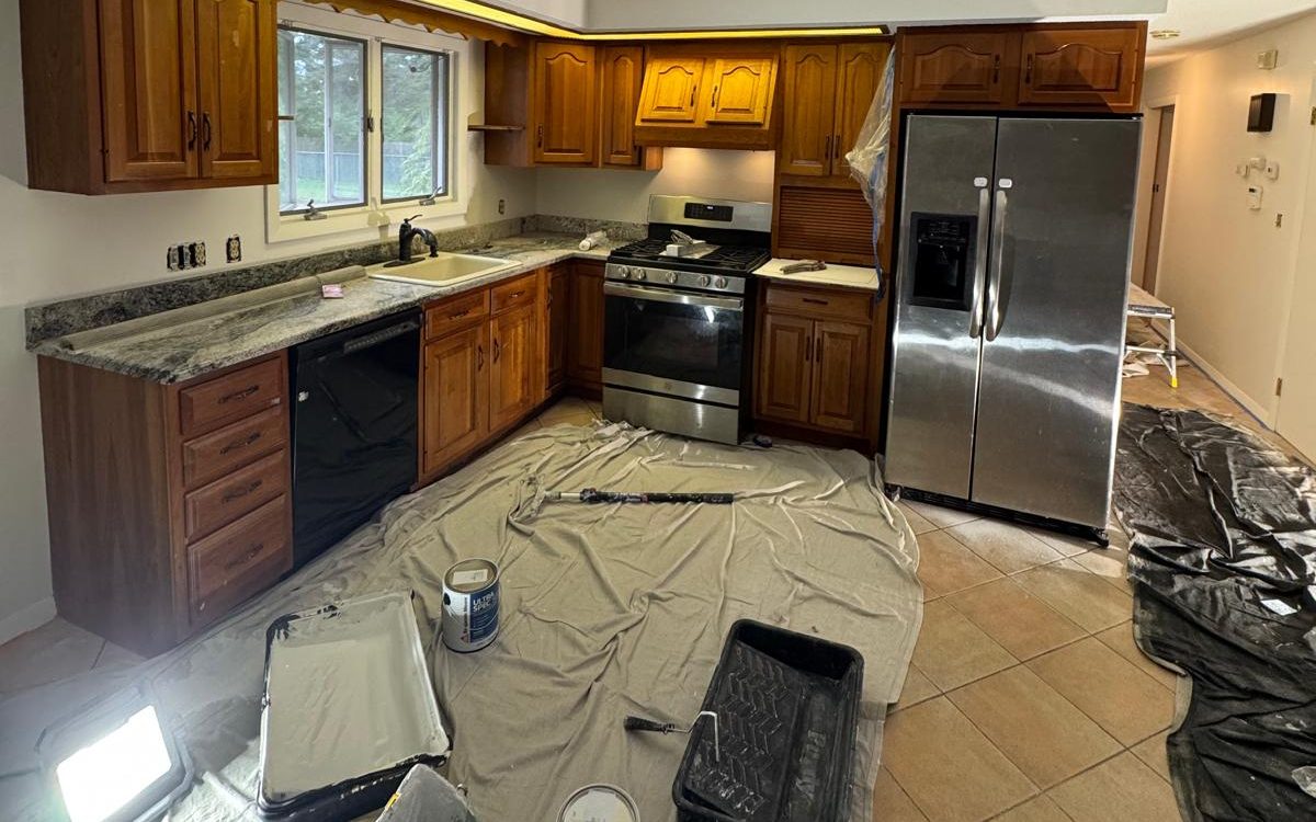 Kitchen with original wood cabinets, protected with drop cloths before painting