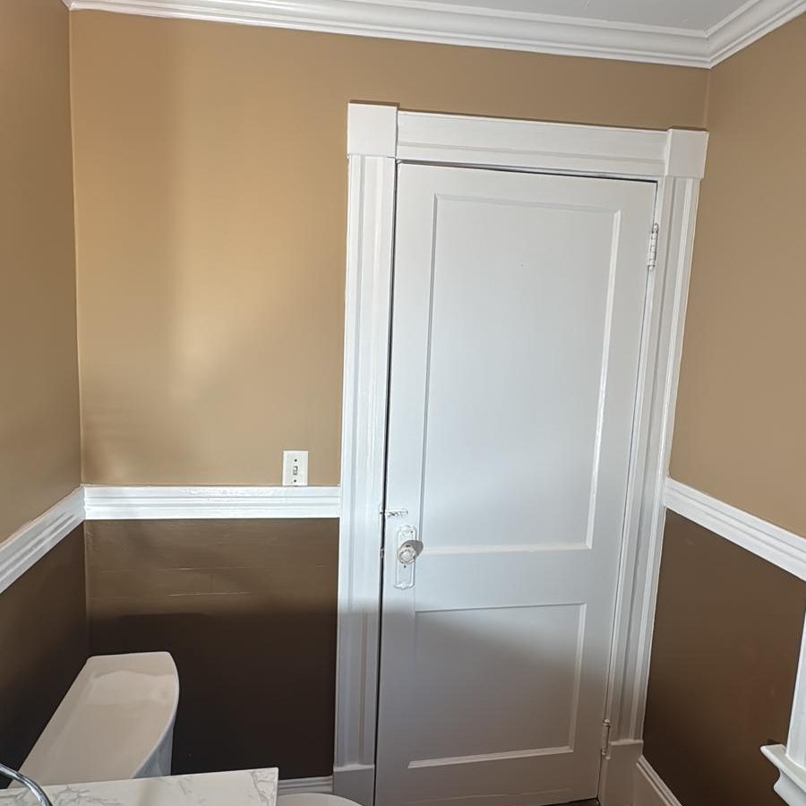 Bathroom with two-tone walls and a freshly painted white paneled door and trim