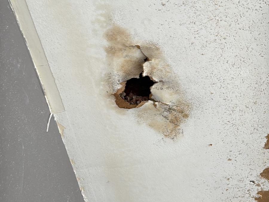 Water-damaged ceiling with a hole that needs drywall repair