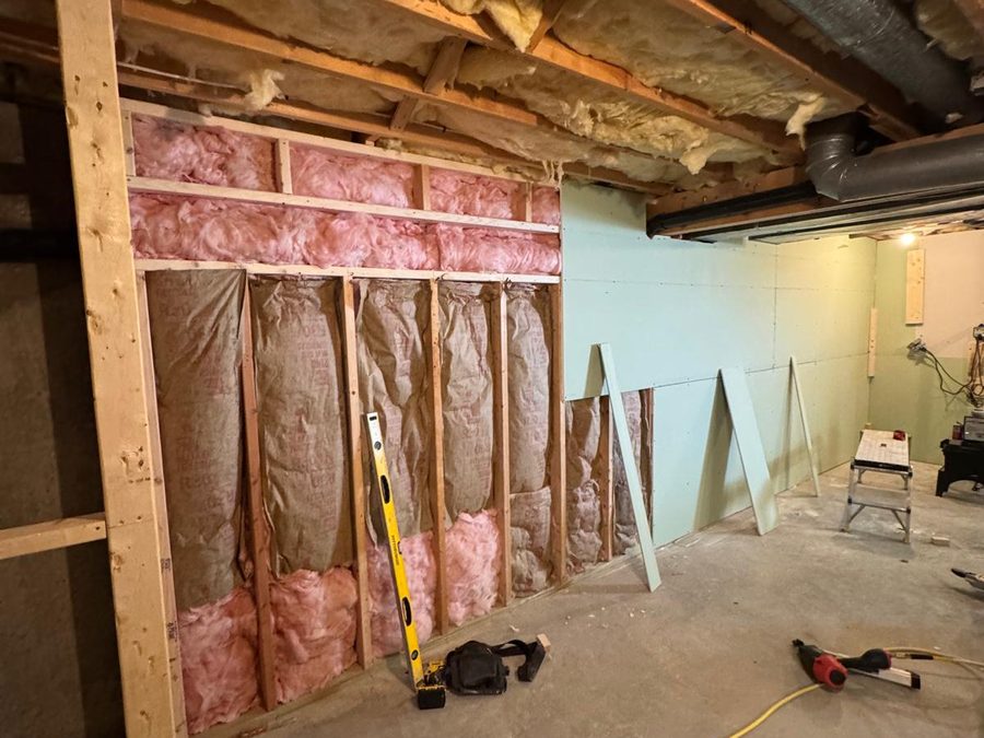 Basement wall with new drywall being hung over insulated framing