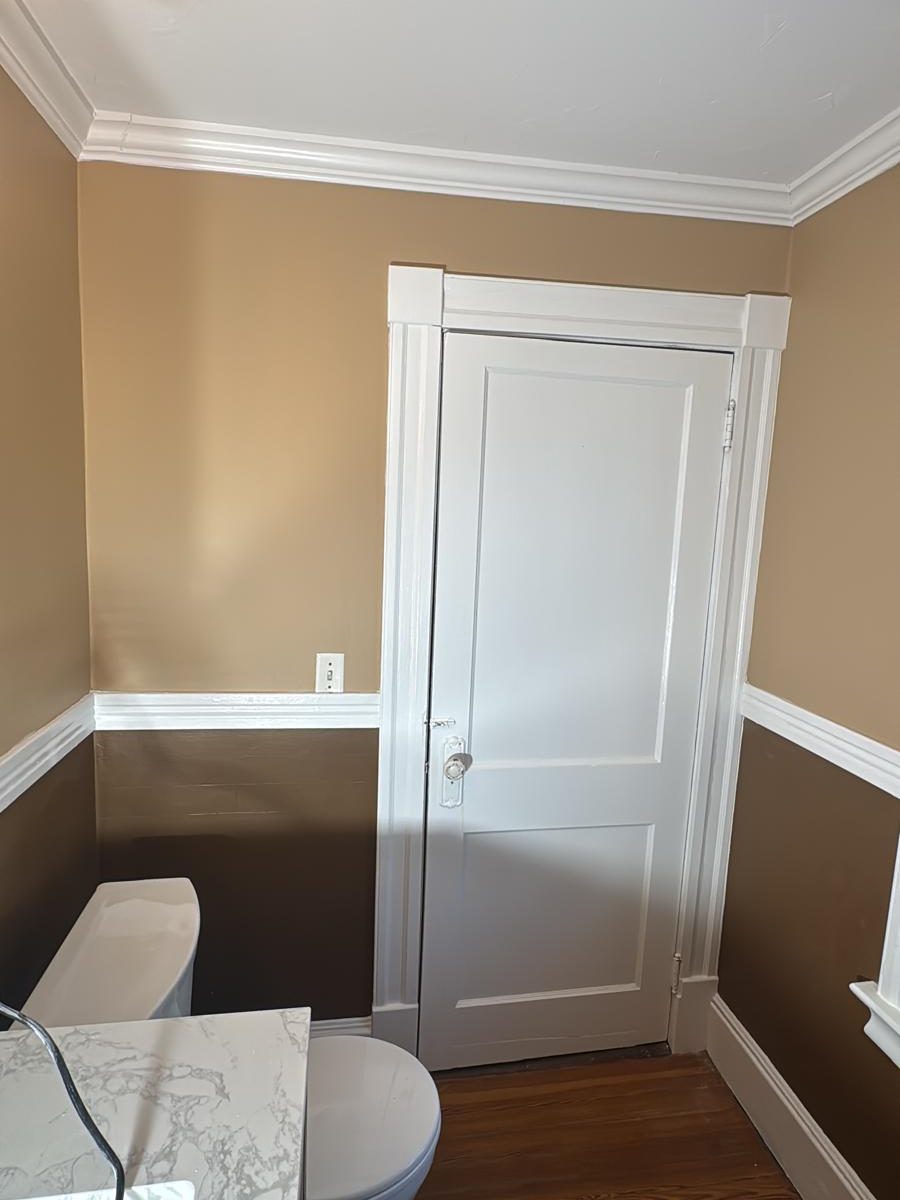 Bathroom with two-tone walls and a freshly painted white paneled door and trim