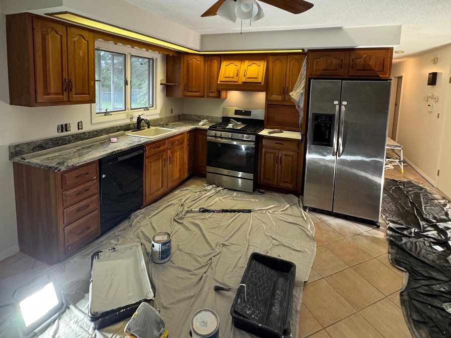 Kitchen with original wood cabinets, protected with drop cloths before painting